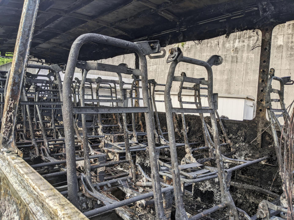 The burnt remains of a bus sits at a facility in Nagoya, Aichi prefecture, central Japan after being transferred from the site of an accident earlier in the day, Monday, Aug. 22, 2022. A passenger bus crashed into a dividing strip, overturned to its side and caught fire on an expressway in central Japan on Monday, leaving two people burned to death and slightly injuring seven others, police said. (Kyodo News via AP)