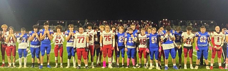 Members of the Winnacunnet and Spaulding high school football teams come together for a moment of silence and pregame tribute to honor the 18 lives that were lost in Wednesday’s mass shooting in Lewiston, Maine.