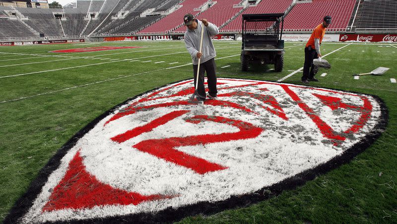 Miguel Tena and Shawn Hughey work a sand and rubber mixture into a Pac-12 logo at Rice-Eccles Stadium in Salt Lake City on April 12, 2011.