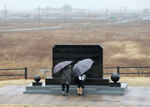 A couple prays in front of a memorial monument in Namie, Fukushima Prefecture, on the eighth anniversary of the 2011 tsunami disaster