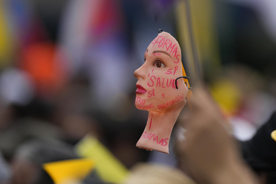 La cara de una muñeca está pintada con mensajes a favor de las reformas propuestas por el gobierno durante una marcha por el Día del Trabajo, en Bogotá, Colombia, el 1 de mayo de 2024. (AP Foto/Fernando Vergara)