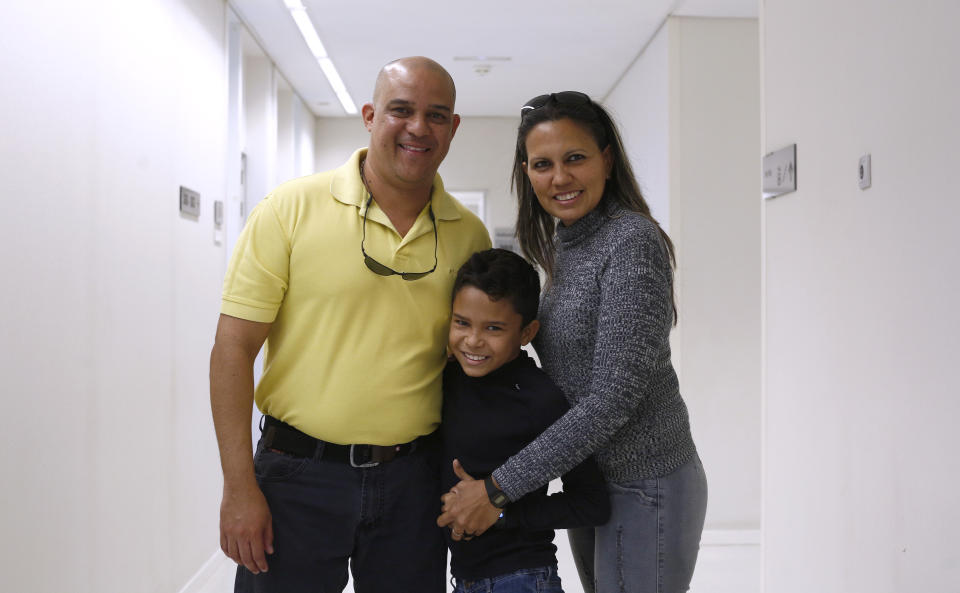 In this Friday, Feb. 22, 2019 photo, Hector Castillo, 11, from Venezuela, center, poses for a picture with his parents Hector Castillo, left, and Luisana Centeno, at the Sant Joan de Deu hospital in Barcelona, Spain. 11-year-old Hector Castillo with at least eight other severely ill children, became the unintended victims of U.S. sanctions against companies tied to the embattled government of Venezuelan leader Nicolas Maduro. Hector suffers from Sickle Cell disease, a disorder that affects hemoglobin, the molecule in red blood cells that delivers oxygen to cells throughout the body. (AP Photo/Manu Fernandez)