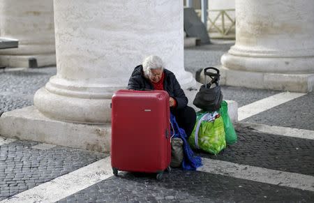 A homeless woman sits with her belongings as she waits for a friend coming out from the Vatican following a visit, under the Bernini's colonnade at the Vatican March 26, 2015. REUTERS/Max Rossi