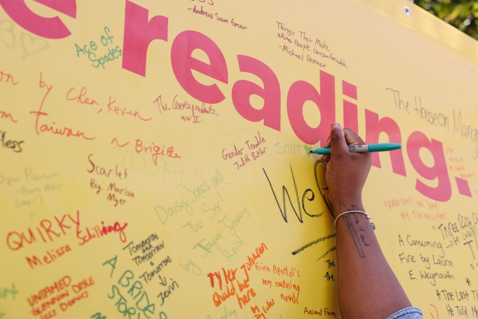 People fill a board with the names of books they love or are currently reading.