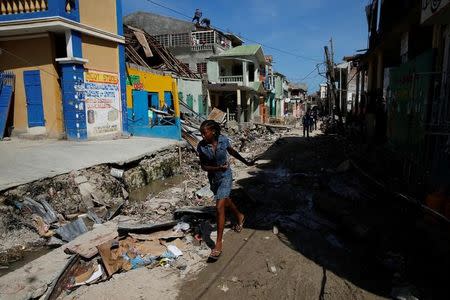 A woman runs on a street filled with rubble and past damaged houses after Hurricane Matthew passes in Jeremie, Haiti, October 8, 2016. REUTERS/Carlos Garcia Rawlins