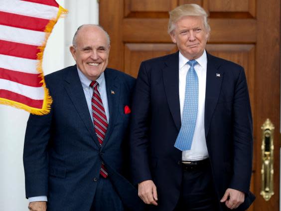 Pictured on 20 November 2016: then-President-elect Donald Trump (right) and former New York Mayor Rudy Giuliani pose for photographs as Giuliani arrives at the Trump National Golf Club Bedminster clubhouse in Bedminster, New Jersey. (AP)