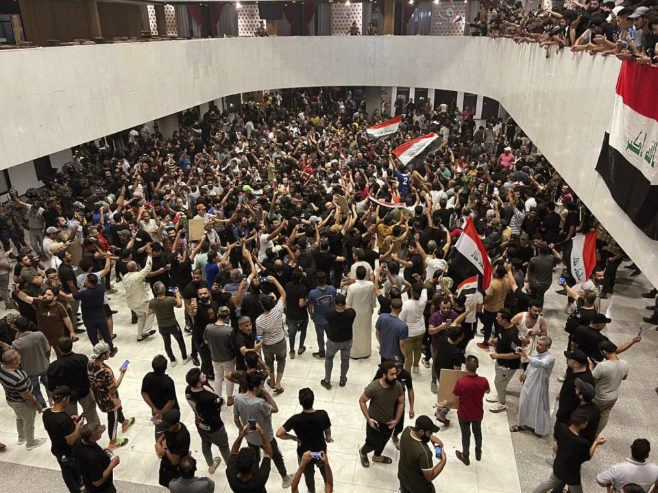 Hundreds of Iraqi protesters breached Baghdad's parliament in Baghdad, Iraq, Wednesday, July. 27, 2022. The majority of the protesters were followers of influential Shiite cleric Muqtada al-Sadr. The demonstrators, all of them men, were seen walking on tables of the parliament floor, sitting in the chairs of lawmakers and waving Iraqi flags. (AP Photo/Ali Abdul Hassan)