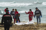 Italian Red Cross volunteers and coast guards recover a body after a migrant boat broke apart in rough seas, at a beach near Cutro, southern Italy, Sunday, Feb. 26, 2023. Rescue officials say an undetermined number of migrants have died and dozens have been rescued after their boat broke apart off southern Italy.(Antonino Durso/LaPresse via AP)
