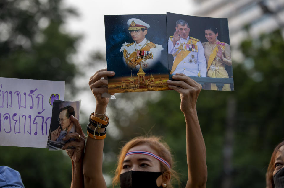 A supporter of the Thai monarchy displays images of King Maha Vajiralongkorn, Queen Suthida and late King Bhumibol Adulyadej during a rally at Lumphini park in central Bangkok, Thailand Tuesday, Oct. 27, 2020. Hundreds of royalists gathered to oppose pro-democracy protesters' demands that the prime minister resign, constitution be revised and the monarchy be reformed in accordance with democratic principles. (AP Photo/Gemunu Amarasinghe)