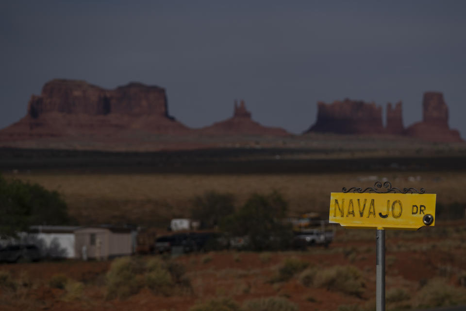 In this April 30, 2020, photo, a sign marks Navajo Drive as Sentinel Mesa, homes and other structures in Oljato-Monument Valley, Utah on the Navajo Reservation, stand in the distance. Even before the pandemic, people living in rural communities and on reservations were among the toughest groups to count in the 2020 census. (AP Photo/Carolyn Kaster)