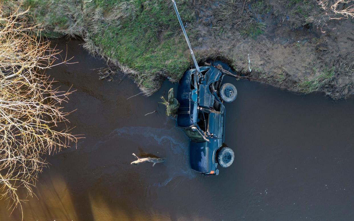 A tractor holds the 4x4 by a strap to prevent it being washed further downstream