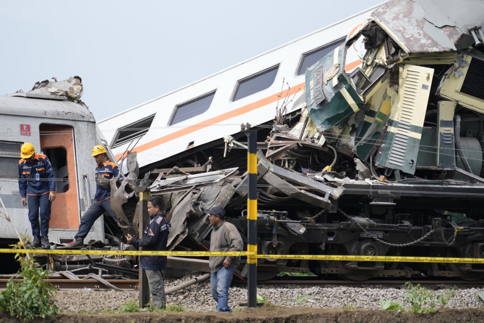 Inspectors work near the wreckage after the collision between two trains in Cicalengka, West Java, Indonesia, Friday, Jan. 5, 2024. The trains collided on Indonesia's main island of Java on Friday, causing several carriages to buckle and overturn, officials said. (AP Photo/Achmad Ibrahim)