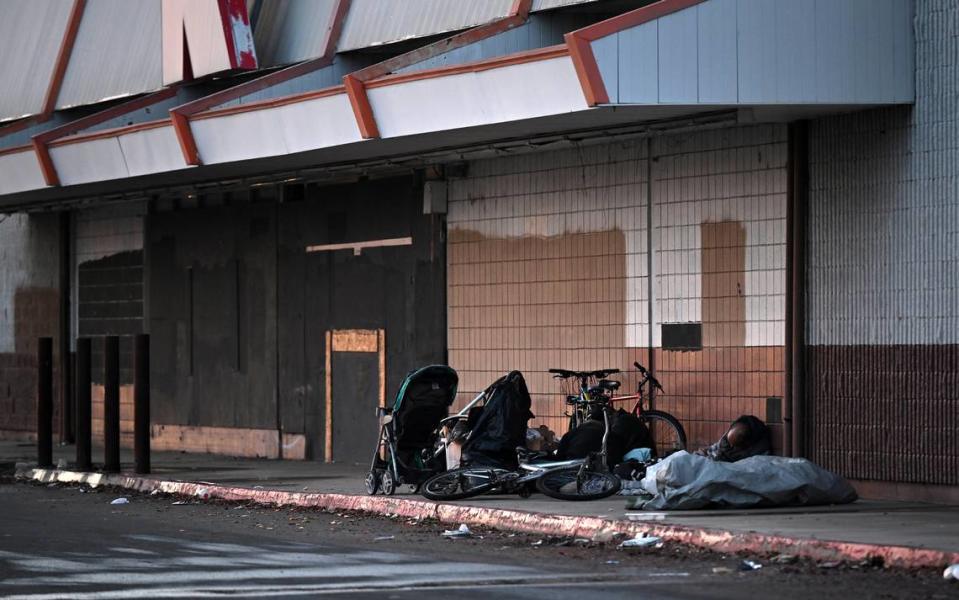 Personas sin hogar se instalan frente a un negocio vacío en Hatch Road en Ceres, California, el jueves 21 de diciembre de 2023.