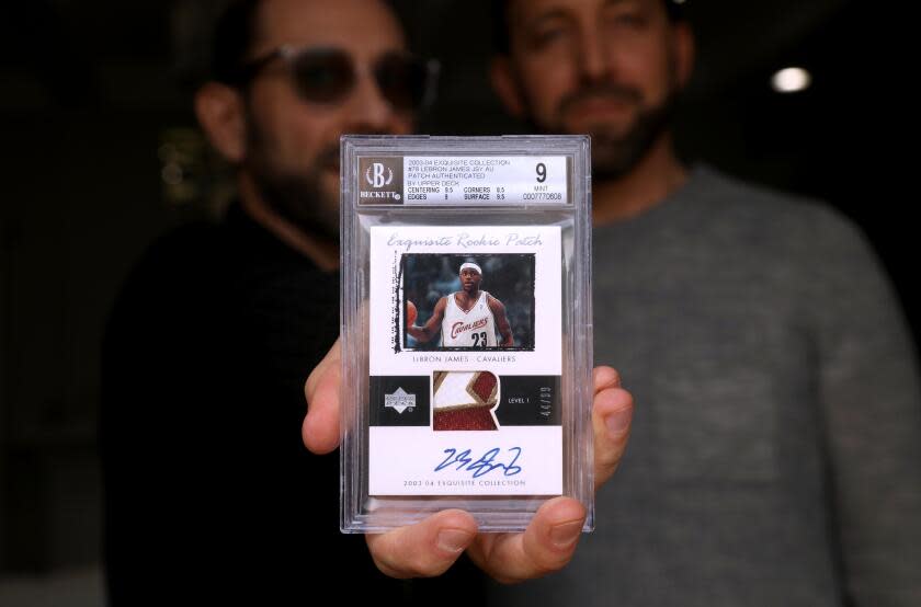 VALLEY VILLAGE, CA - JANUARY 17, 2024 - - Steven Spiegel, left, next to his brother Alan, holds a LeBron James rookie card valued at about $1 million at his home in Valley Village on January 17, 2024. The Spiegel brothers are co-owners of the card. The 2003-2004 card, which has Lebron's autograph on it and a swatch of his jersey, is the subject of litigation - the Spiegel's allege that Goldin Auctions breached a contract to auction the card in 2022. The card was pulled from a Goldin auction after online chatter from a shadowy Instagram account called "Card Porn" cast doubt on the special rookie card's authenticity. The Spiegel's have sought damages from Goldin, which is led by high-profile card industry player Ken Goldin, and say their lawsuit is about making the hobby safe for kids. (Genaro Molina/Los Angeles Times)