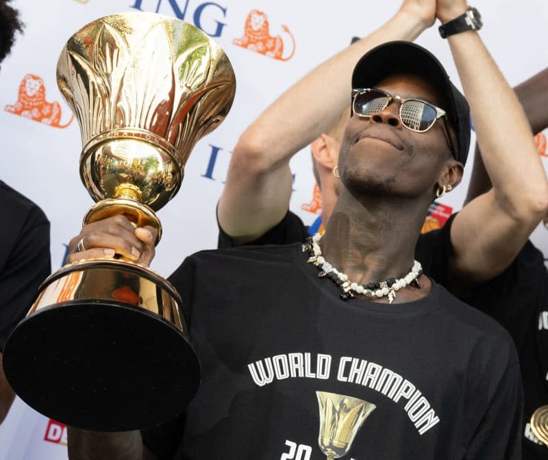 Dennis Schroeder, captain of the German national basketball team, holds up the trophy during the team's reception in Frankfurt. Captain Dennis Schroeder believes that world champions Germany can compete for Olympic basketball gold in summer even though the United States are set to send many of their best players to the Paris Games. Boris Roessler/dpa