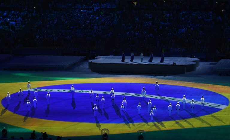 Brazil's national flag is projected onto the playing field as singers perform the country's national anthem during the closing ceremony of the Rio 2016 Olympic Games