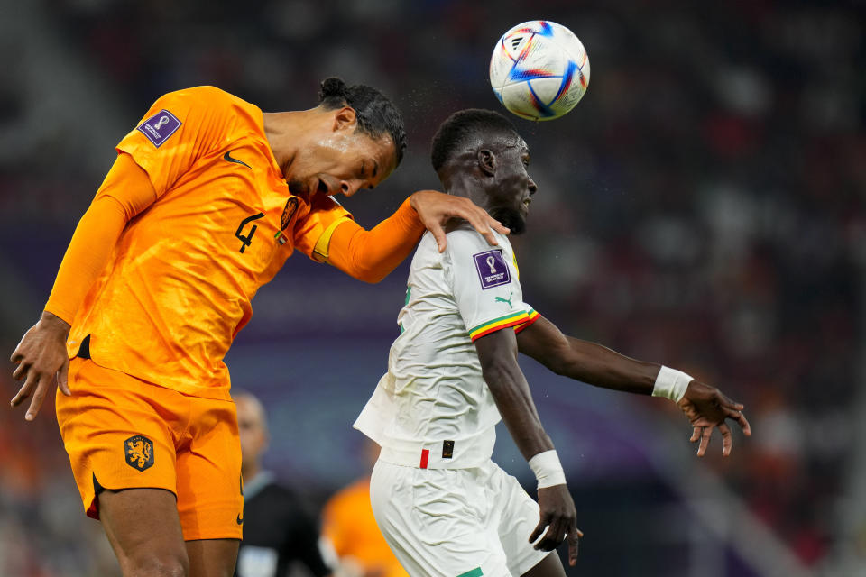 Virgil van Dijk, de Holanda (izquierda), y el senegalés Idrissa Gueye saltan por un balón durante un juego del Grupo A del Mundial que enfrentó a ambos equipos, en el estadio Al Thumama, en Doha, Qatar, el 21 de noviembre de 2022. (AP Foto/Petr David Josek)