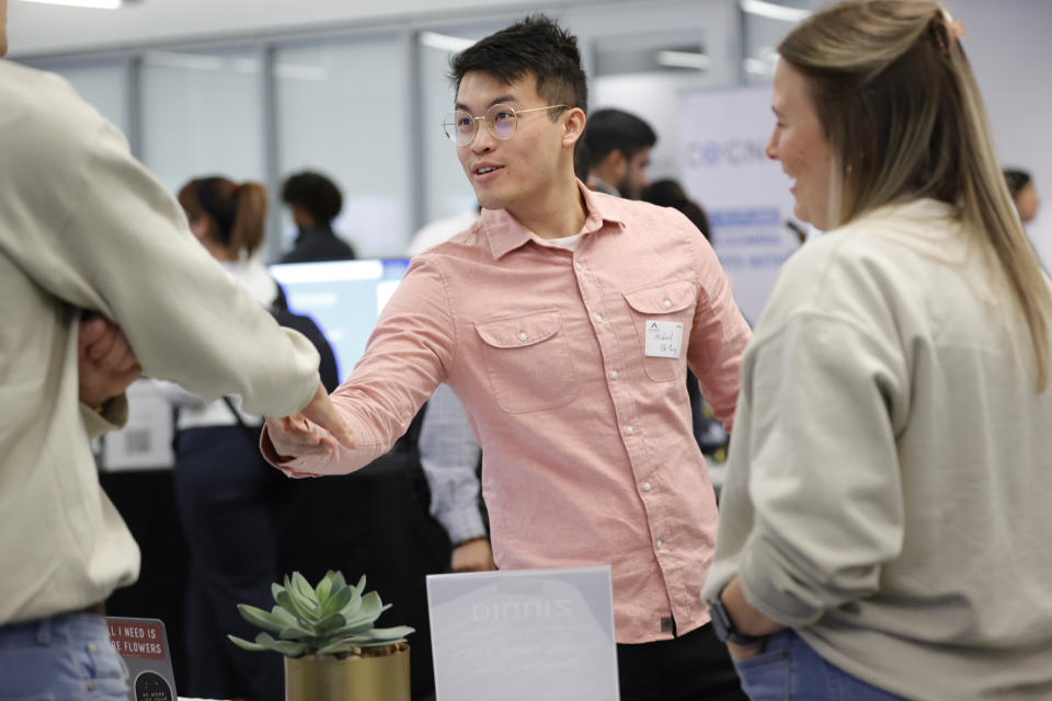 File - Georgia Tech student Michael Oh-Yang, center, greets company representatives at a job fair on March 29, 2023, in Atlanta. On Friday, the U.S. government issues its latest monthly jobs report. (AP Photo/Alex Slitz, File)