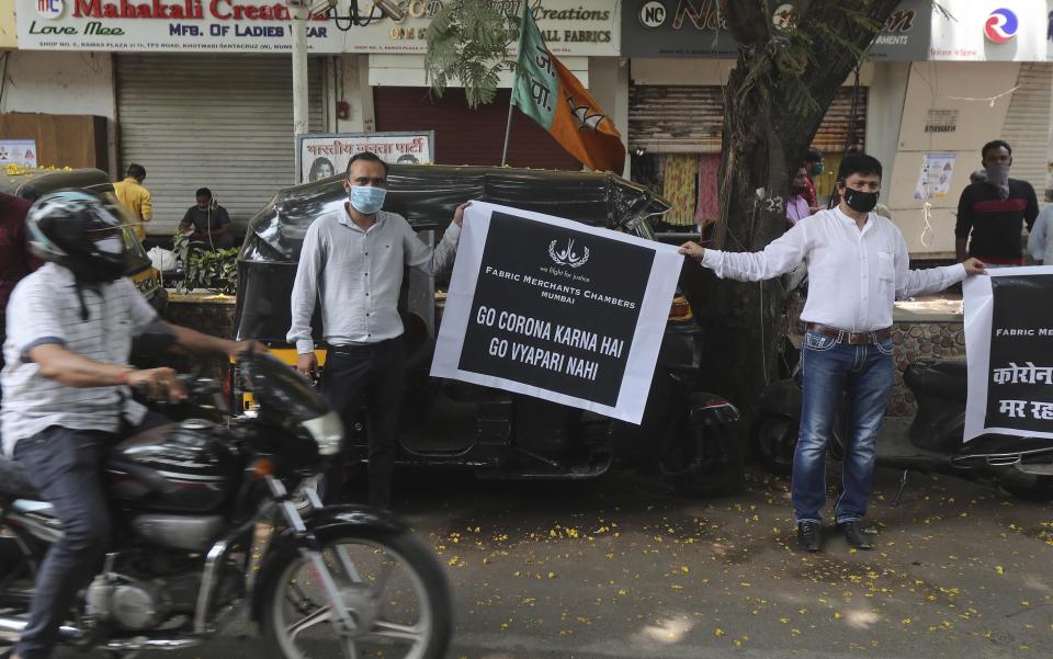 Shop owners hold banners against a partial lockdown imposed by the Maharashtra state government, in Mumbai, India, Thursday, April 8, 2021. India has a seven-day rolling average of more than 100,000 cases per day and has reported 13 million virus cases since the pandemic began, the third-highest total after the United States and Brazil. The western Maharashtra state, home to financial capital Mumbai, is the worst-hit and has nearly half of the country new infections in the past week. (AP Photo/Rafiq Maqbool)