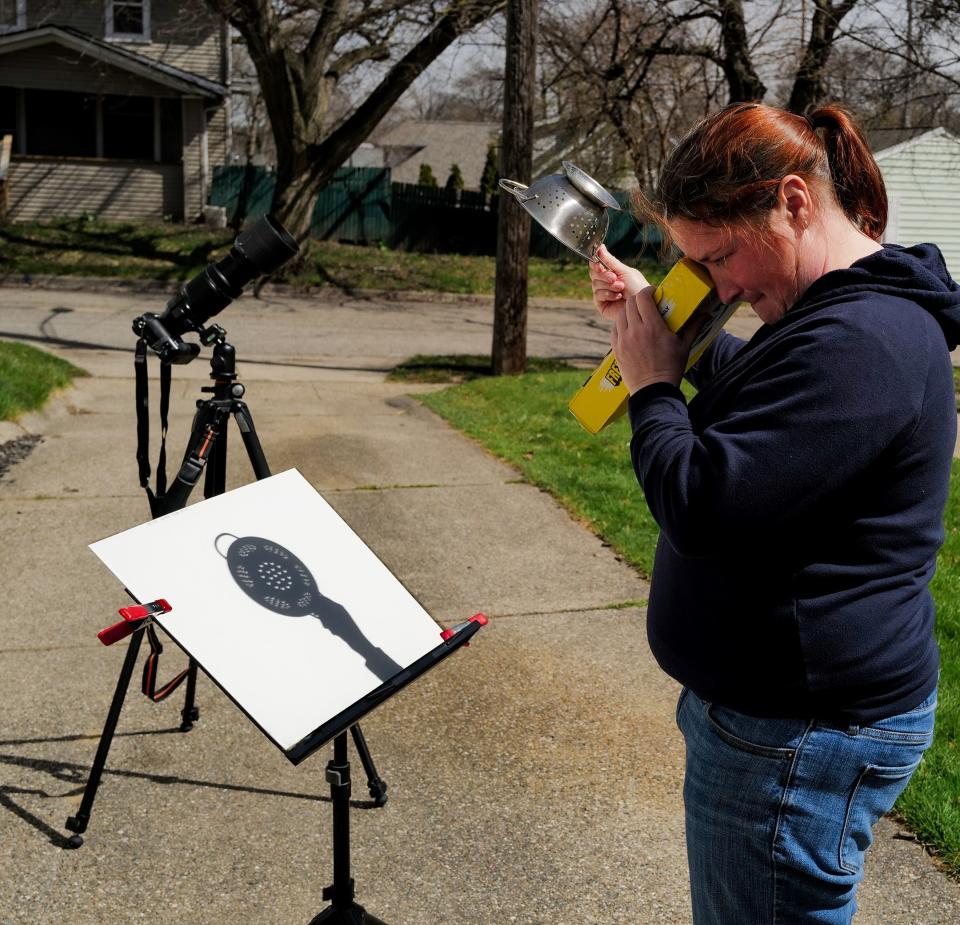 Lansing resident Ashley McElmurry uses a homemade pinhole camera and a colander to view the solar eclipse Monday, April 8, 2024.