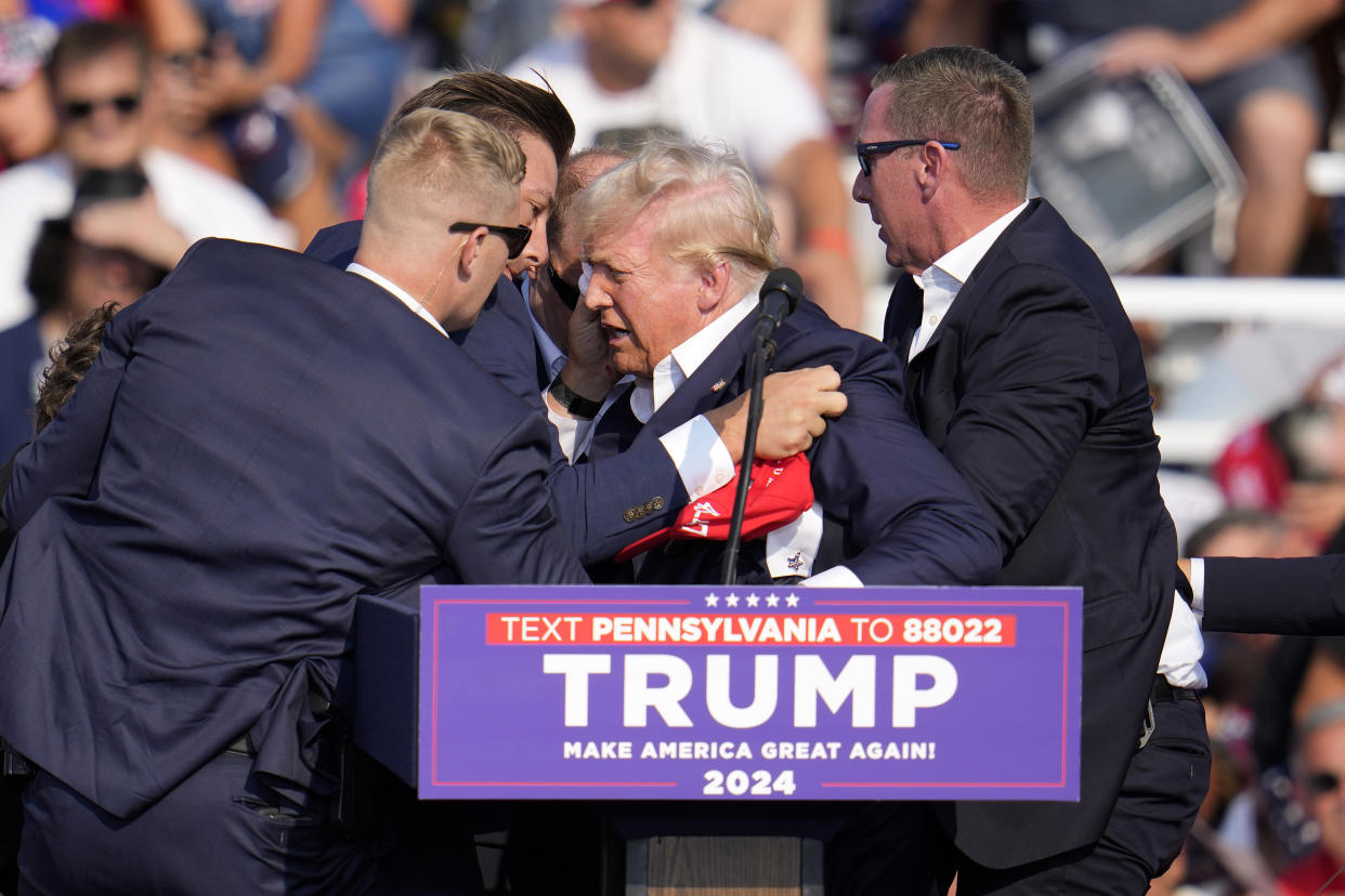 Former President Donald Trump is helped off the stage after being shot at a campaign event in Butler, Pa.