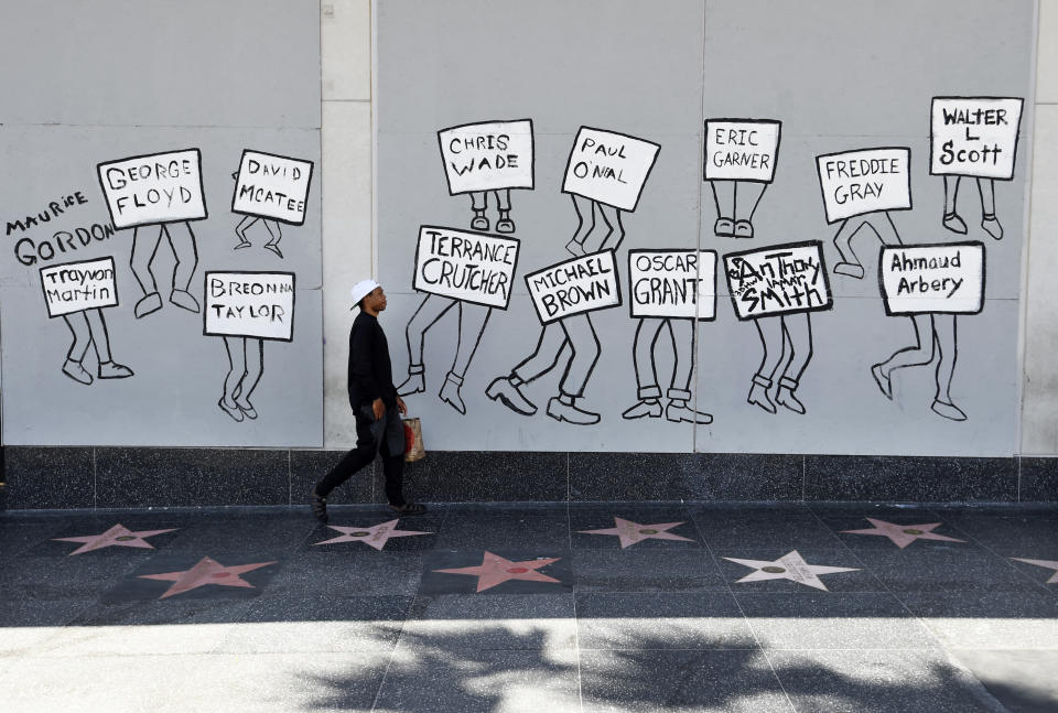 A man walks past a mural of black victims of police brutality on Hollywood Blvd., a day after a large protest march there, Monday, June 15, 2020, in Los Angeles. Protests continue to be held in U.S. cities over the death of George Floyd, a black man who died after being restrained by Minneapolis police officers on May 25. (AP Photo/Chris Pizzello)
