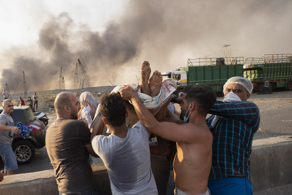 People evacuate a wounded person after a massive explosion in Beirut, Lebanon, Tuesday, Aug. 4, 2020. (AP Photo/Hassan Ammar)