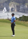 Brooks Koepka of the United States checks his smart phone as he hold the pin flag on the 5th green during a practice round ahead of the start of the British Open golf championships at Royal Portrush in Northern Ireland, Tuesday, July 16, 2019. The British Open starts Thursday. (AP Photo/Jon Super)