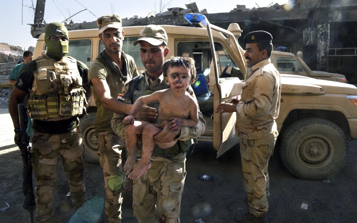 A young boy was found by Iraqi army soldiers eating raw meat in the rubble. He was believed to be foreign as medics could not understand his language - Carol Guzy/Rex