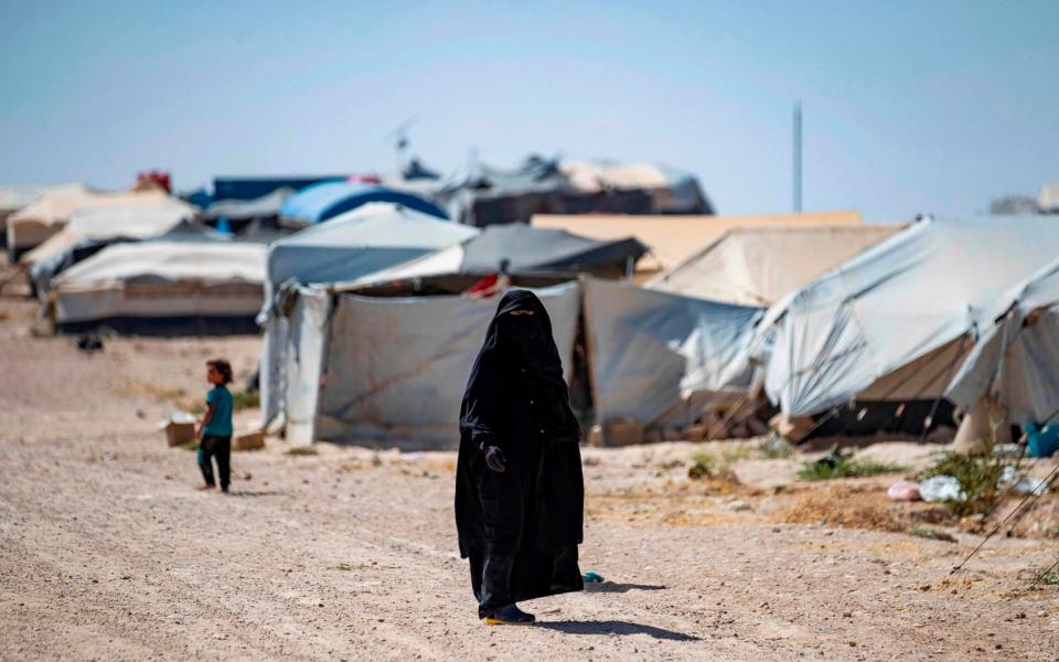 A woman walks through Al Hol camp in northeastern Syria - AFP