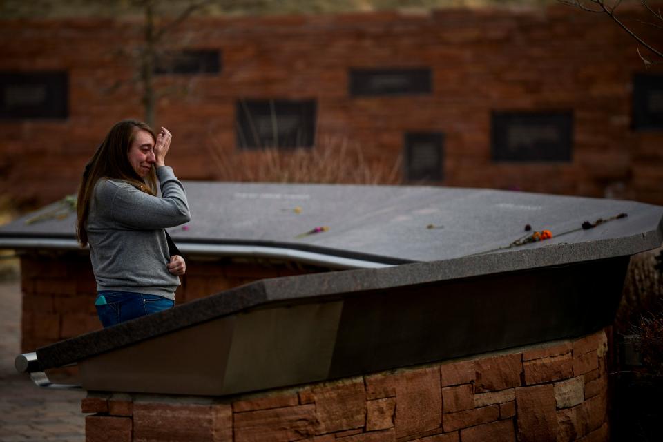 Nicole Boudreau, who was a freshman at Columbine High School during the 1999 mass shooting, wipes away a tears as she visits the Columbine Memorial in Littleton, Colo. on April 2, 2019.
