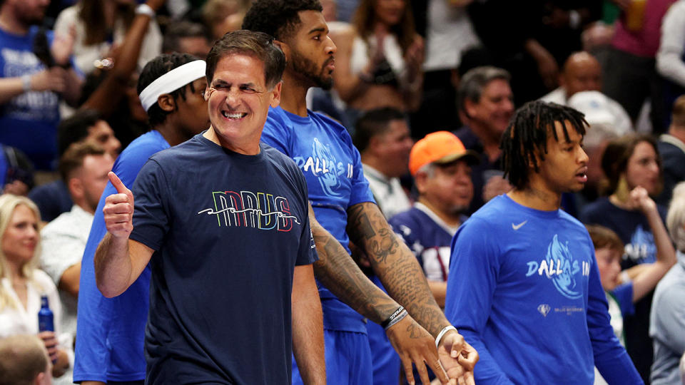 Dallas Mavericks NBA owner Mark Cuban is pictured giving a thumbs up in front of his team's bench.