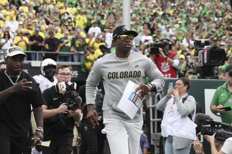 Colorado coach Deion Sanders runs onto the field before leading his team against Oregon