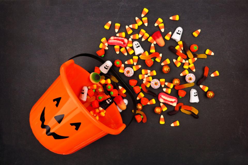 Halloween Jack o Lantern pail with spilling candy sitting on a dark background