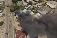 In this image made from aerial video, smoke rises from burning buildings during a protest in the capital of Honiara, Solomon Islands, Thursday, Nov. 25, 2021. Prime Minister Manasseh Sogavare declared a lockdown after about 1,000 people took to the streets in the capital for a second day, demanding his resignation over a host of domestic issues, according to local media reports. (Australian Broadcasting Corporation via AP)