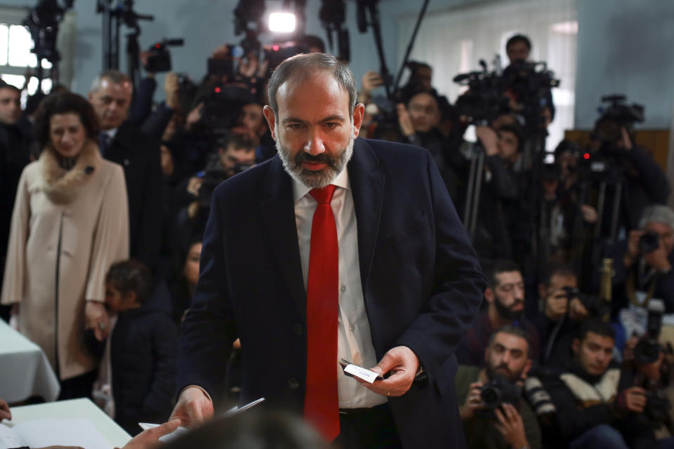 Acting Armenian Prime Minister Nikol Pashinian, c enter, prepares to cast his ballot in a polling station during an early parliamentary election in Yerevan, Armenia, Sunday, Dec. 9, 2018. The charismatic 43-year-old Nikol Pashinian took office in May after spearheading massive protests against his predecessor's power grab that forced the politician to step down. (Vahan Stepanyan/PAN Photo via AP)