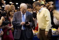 Berkshire Hathaway CEO Warren Buffett gets his wallet out to pay a bet to Microsoft co-founder Bill Gates after participating in a newspaper throwing contest prior to the Berkshire annual meeting in Omaha, Nebraska, May 2, 2015. REUTERS/Rick Wilking