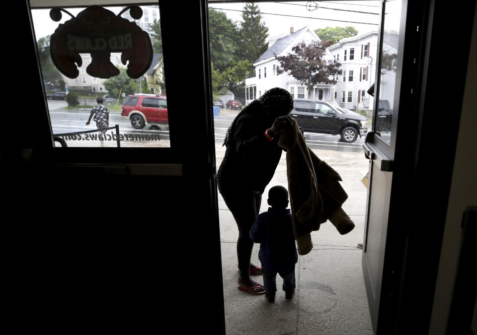 In this June 13, 2019 photo, a migrant woman and young boy prepare for rain outside the Portland Exposition Building in Portland, Maine. Maine's largest city has repurposed the basketball arena as an emergency shelter in anticipation of hundreds of asylum seekers who are headed to the state from the U.S. southern border. Most are arriving from Congo and Angola. (AP Photo/Elise Amendola)