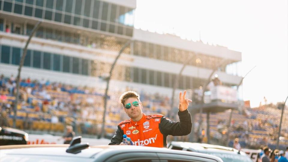 a person in an orange jacket waving from a car