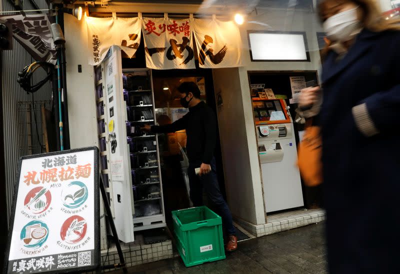 Staff member of Takenoko ENT Clinic replenishes COVID-19 test kit to a vending machine in Tokyo
