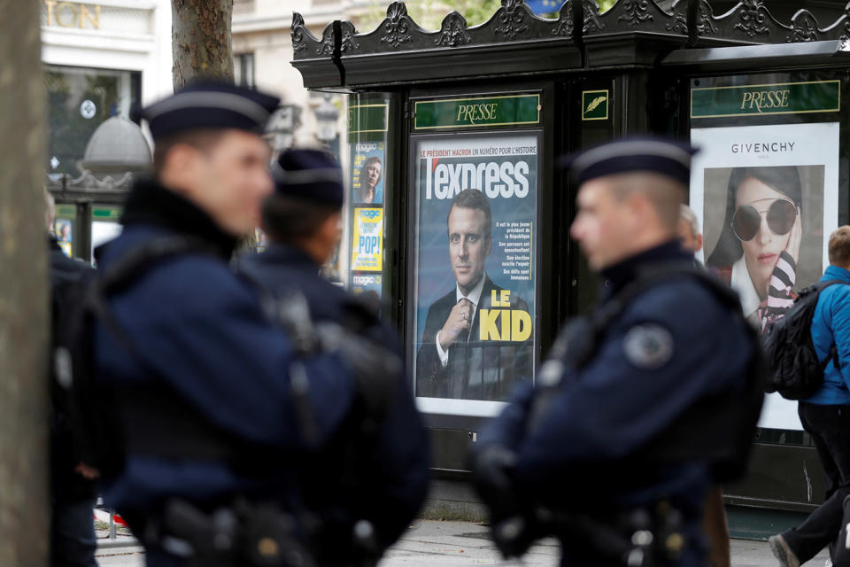 Police near newsstand image of Emmanuel Macron