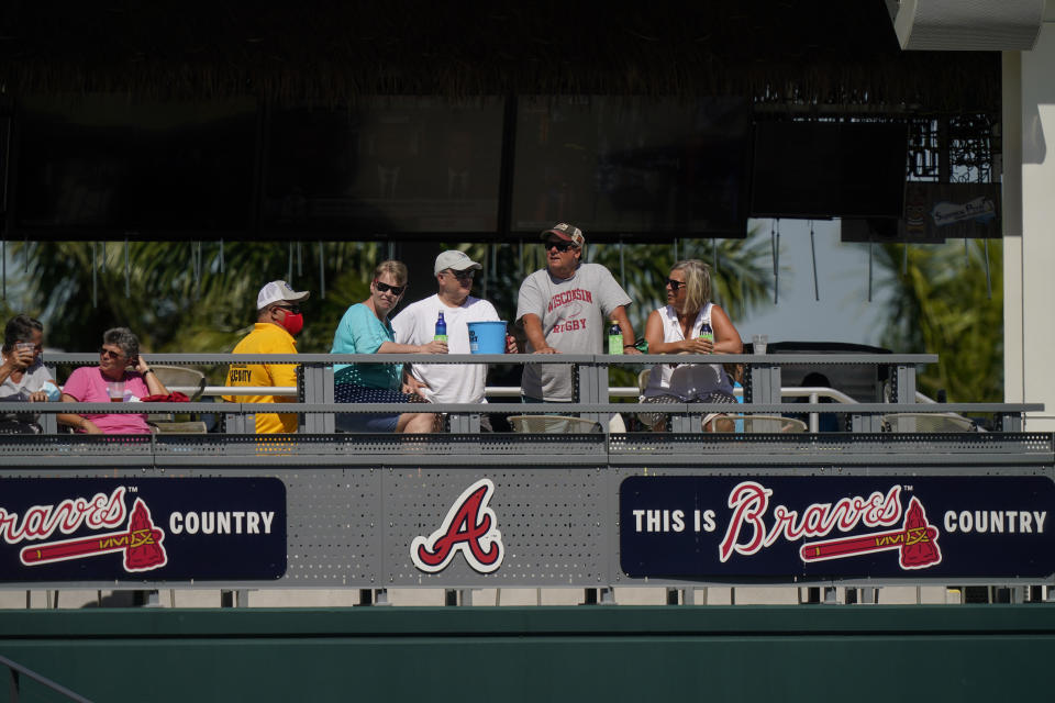 Baseball fans watch from a distance as the Atlanta Braves workout during spring training baseball practice on Tuesday, Feb. 23, 2021, in North Port, Fla. (AP Photo/Brynn Anderson)