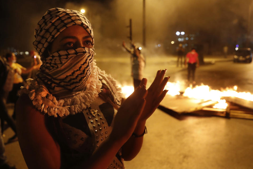 An anti-government protester shouts slogans next to burning tires and woods, during a protest against the political leadership they blame for the economic and financial crisis, in front of the government house, in downtown Beirut, Lebanon, Thursday, June 11, 2020. (AP Photo/Hussein Malla)