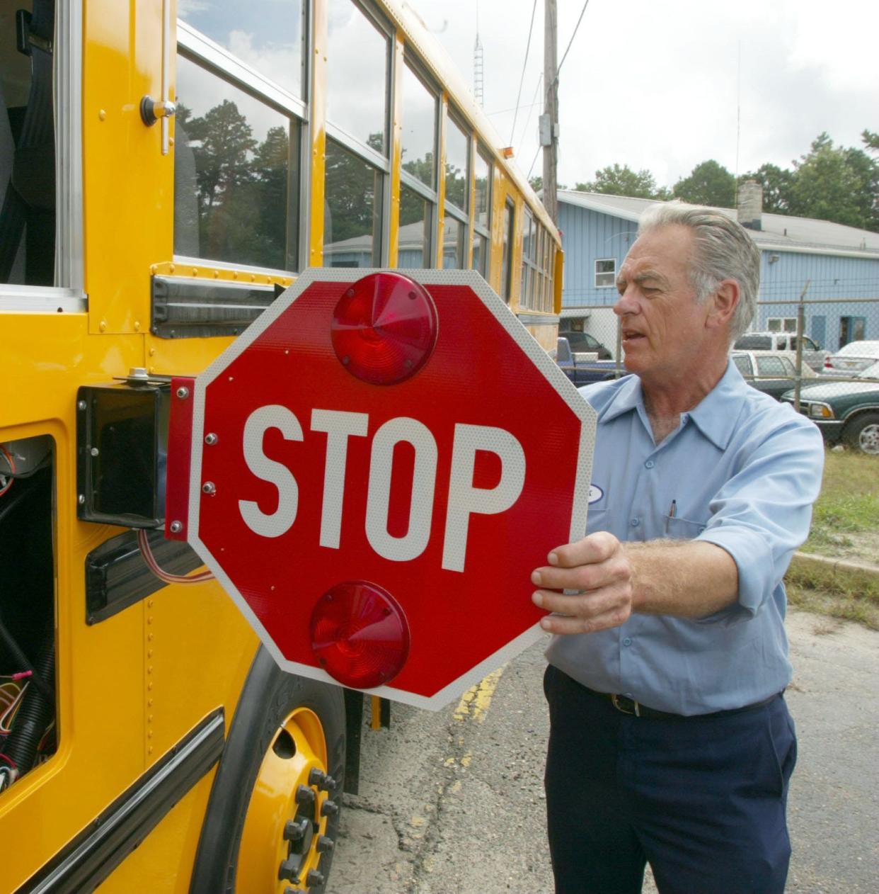 An employee for the Jackson Township School District extends a stop sign on one of the township's school buses in this file photo.