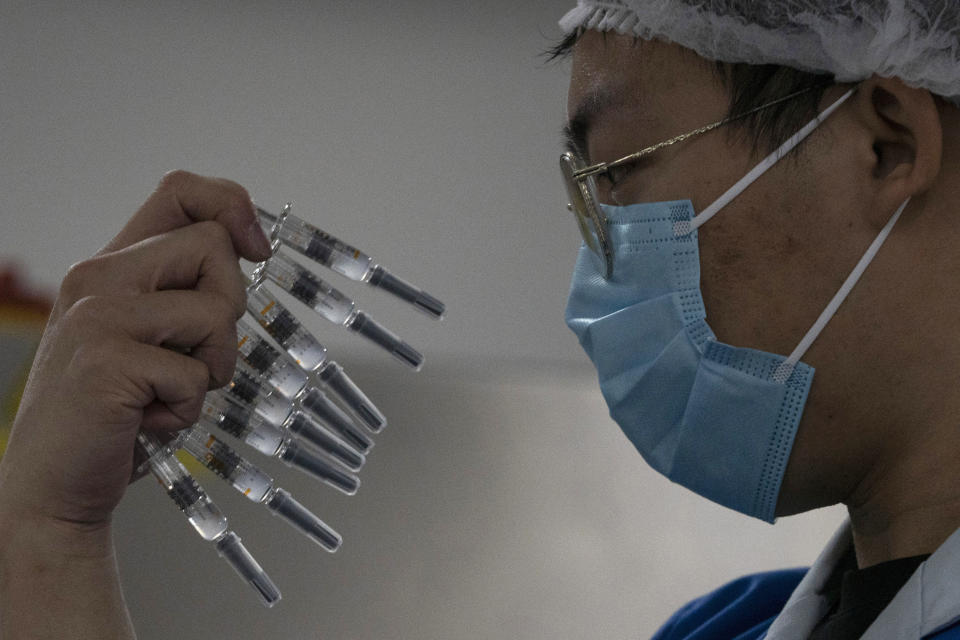 FILE - In this Thursday, Sept. 24, 2020 file photo, a worker inspects syringes of a vaccine for COVID-19 produced by Sinovac at its factory in Beijing. Sinovac and Sinopharm both rely on a traditional technology called an inactivated virus vaccine, based on cultivating batches of the virus and then killing it. (AP Photo/Ng Han Guan)