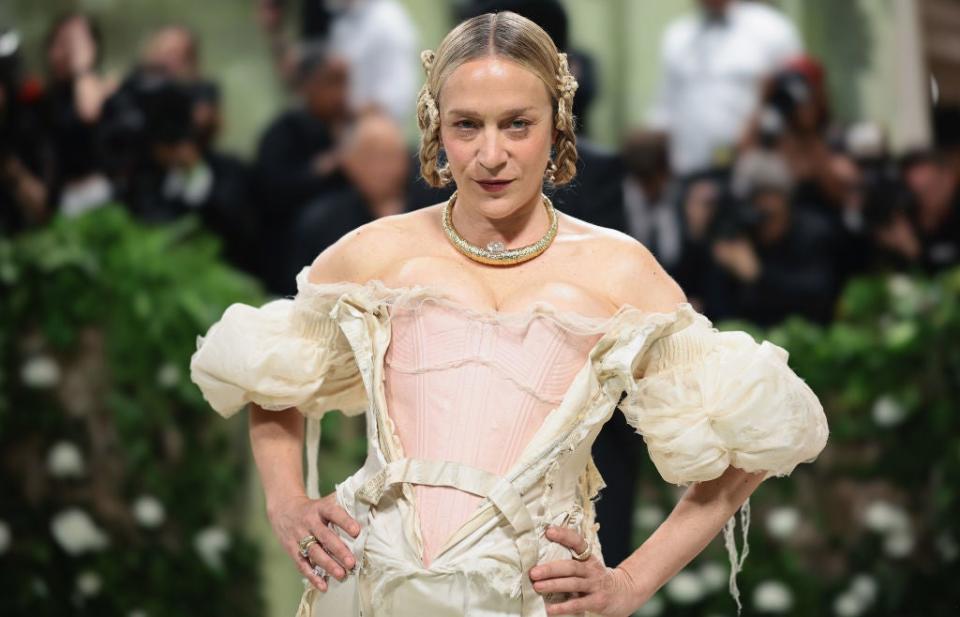 Chloë Sevigny poses on the red carpet wearing an off-the-shoulder, vintage-style gown with puff sleeves and a corset bodice