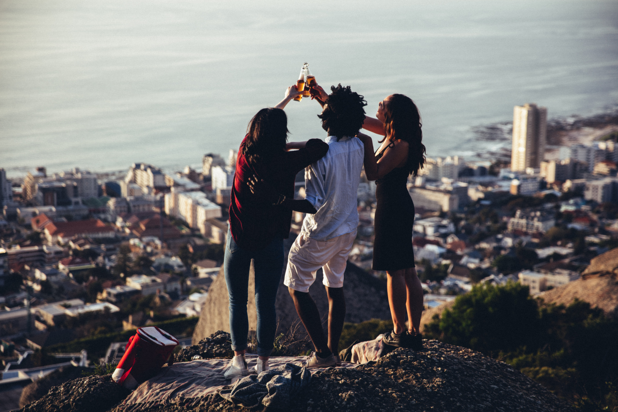 Three Friends With Bottles of Beer, Standing on the Mountain Overlooking Coast of Cape Town, Africa