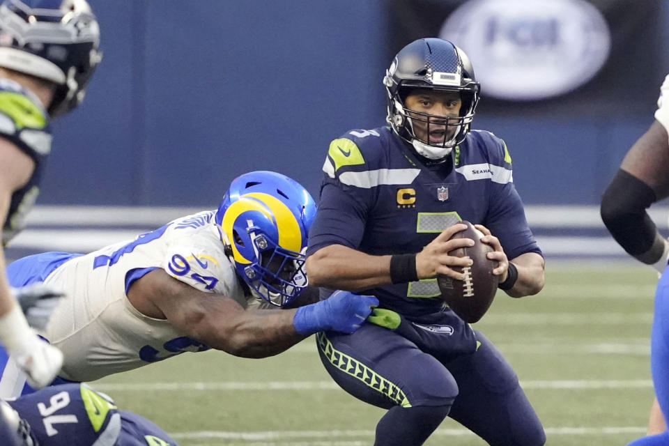 Seattle Seahawks quarterback Russell Wilson, right, eyes a receiver as Los Angeles Rams defensive tackle A'Shawn Robinson grabs him during the second half of an NFL wild-card playoff football game, Saturday, Jan. 9, 2021, in Seattle. (AP Photo/Ted S. Warren)