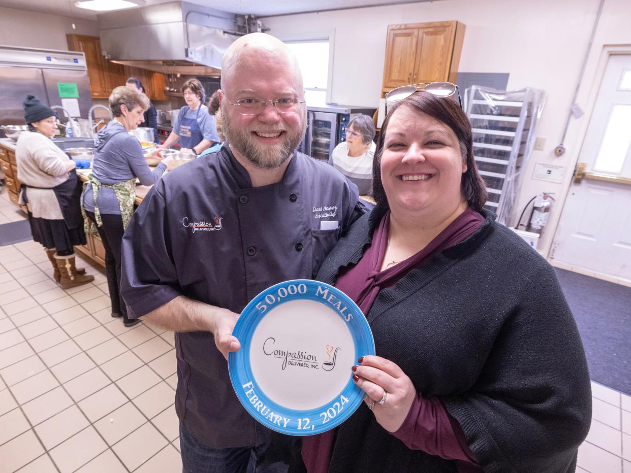 Amanda and Daniel Anschutz, co-founders of Compassion Delivered, hold a commemorative plate marking their 50,000th delivery meal. The effort is based out of the kitchen at Evermore Community Church in Lake Township.