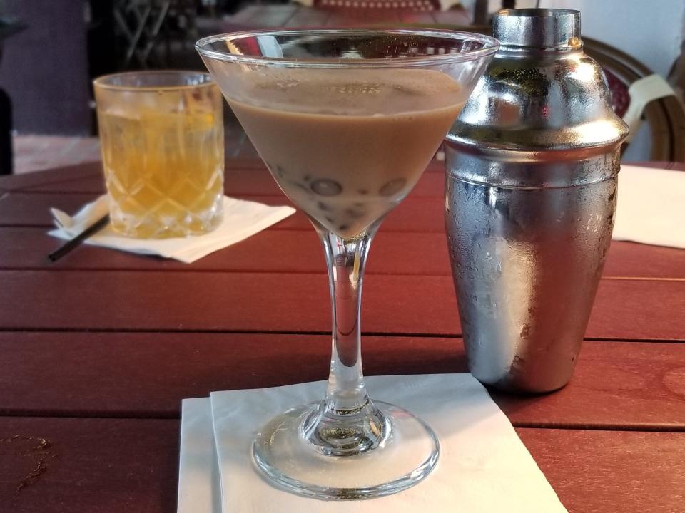 Chocolate martini in front of cocktail shaker on wood table